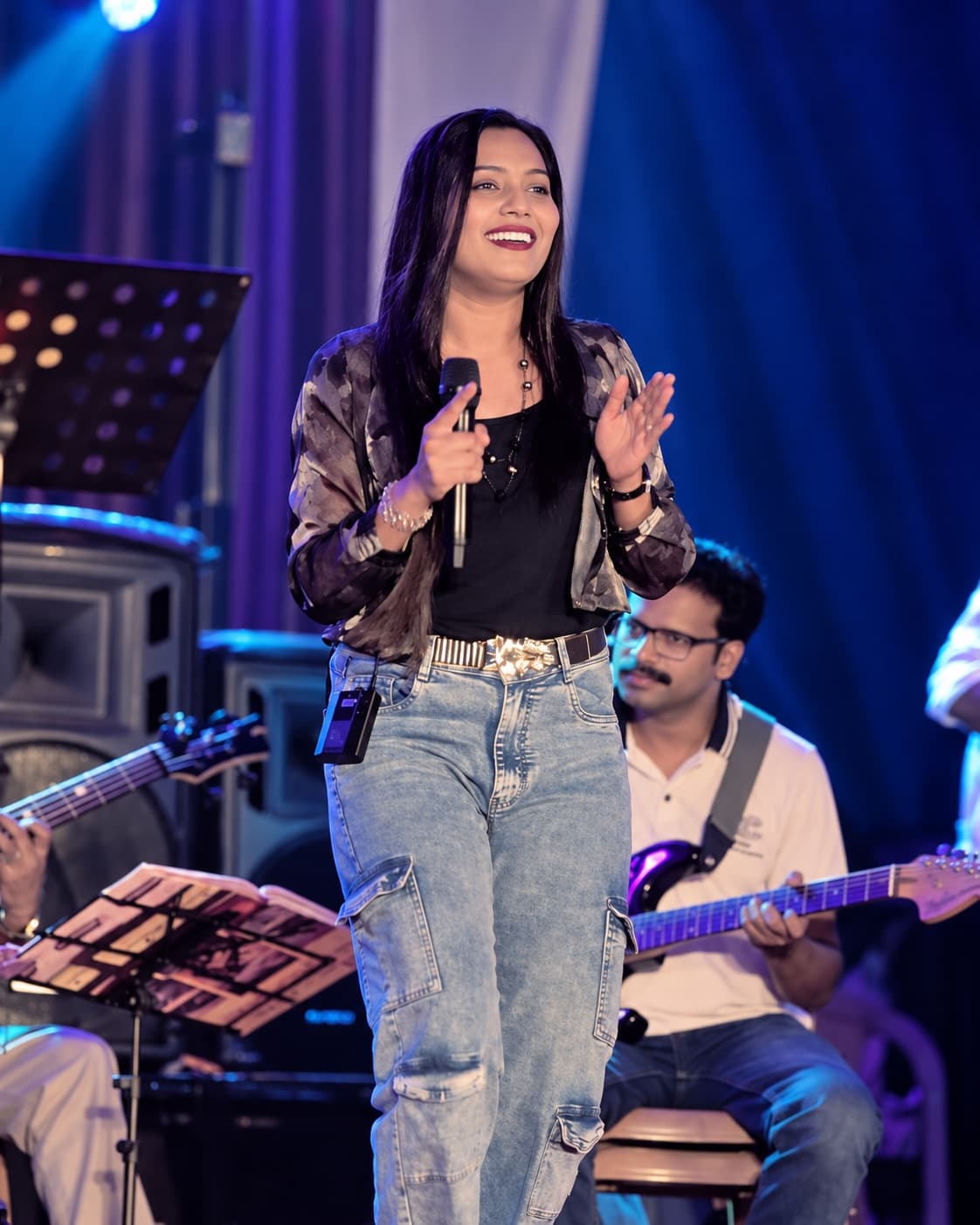 Originals Orchestra singer in a black jacket holding a microphone on stage